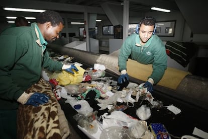 Two workers manually separate garbage at the Valdemíngomez waste plant.