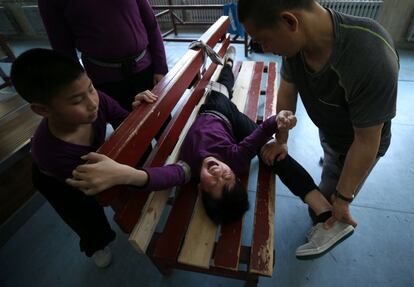 Un profesor estira las piernas de un niño durante un entrenamiento en la escuela Ópera de Shenyang, en la provincia de Liaoning, China.