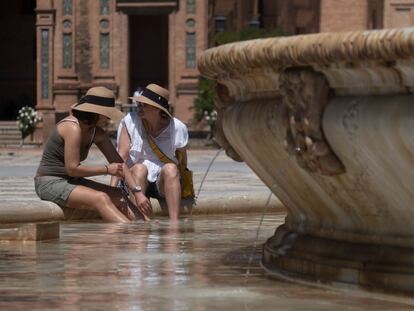 Dos mujeres se refrescan en la fuente de la plaza de España, este miércoles en Sevilla.
