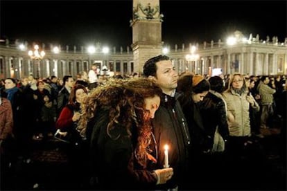 Dos jóvenes rezan en medio de una gran multitud anoche en la plaza de San Pedro tras conocer la muerte del Papa.