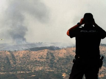 Un polic&iacute;a observa el incendio de Cerro Muriano.