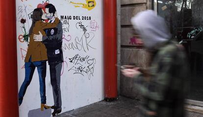Un hombre pasa frente a un poster realizado por el artista TvBoy que representa a Mariano Rajoy besando a Inés Arrimadas.