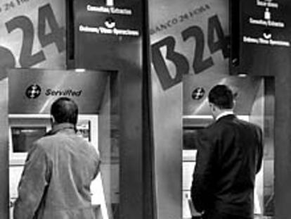 Dos usuarios, en los cajeros de una sucursal bancaria madrileña.