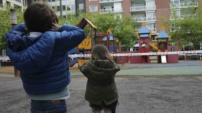 Un niño y una niña frente a un parque infantil.