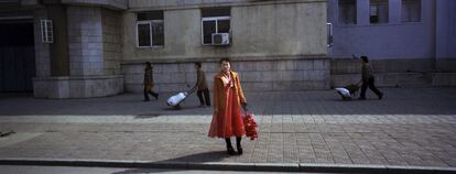 7 de abril del 2012. Una mujer se encuentra en la orilla de un camino con flores artificiales después de regresar de un ensayo para un desfile masivo previsto para finales de la semana para honrar a los líderes norcoreanos en Pyongyang.