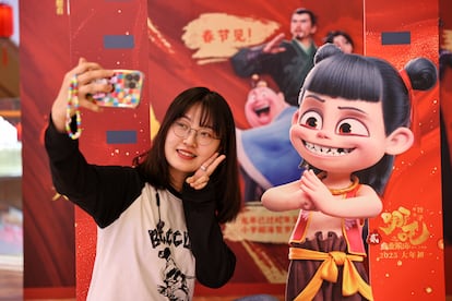 Una niña se hace un selfi delante del cartel con el protagonista de la película 'Ne Zha 2', en la localidad de Shenyang, el 12 de febrero.