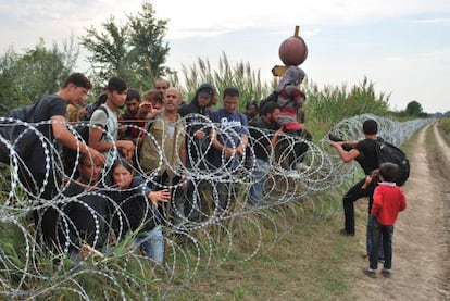 Varios refugiados sirios intentan saltar la alambrada de la frontera entre Hungr&iacute;a y Serbia.