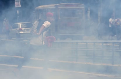 Un joven corre entre el humo de gases lacrimógeno lanzados por la policía.