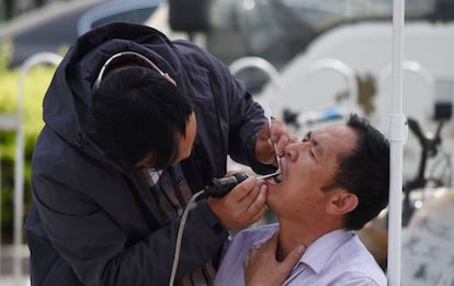 Un dentista atiende a un paciente en las calles de Pek&iacute;n, la semana pasada.