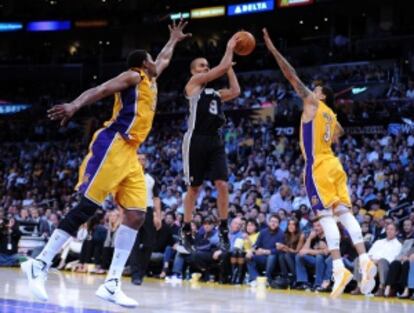 Tony Parker, de los Spurs, pasa la pelota entre Andrew Bynum, a la izquierda, y Matt Barnes.