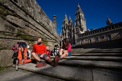 Dos peregrinos descansan en las escaleras de la Plaza del Obradoiro, frente a la Catedral de Santiago de Compostela.