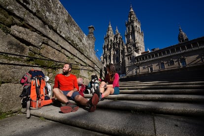 Dos peregrinos terminan el Camino de Santiago y descansan en las escaleras de la Plaza del Obradoiro en frente de La Catedral. 