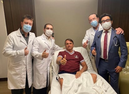 El presidente  de Brasil, Jair Bolsonaro, levanta un dedo en señal de aprobación rodeado de los médicos que le atendieron su última hospitalización