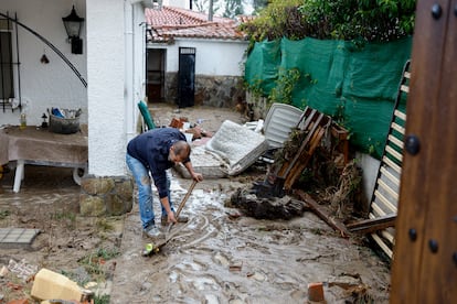 Un hombre retiraba este lunes el lodo acumulado en su vivienda de Aldea del Fresno en Madrid, a causa de las fuertes lluvias registradas. 