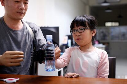 Angel Peng, 8, who injured her hand in a scalding accident when she was nine months old, reacts as she tries to hold a bottle with a 3D-printed prosthetic hand designed and built by engineer Chang Hsien-Liang, in Taoyuan, Taiwan, April 6, 2017. REUTERS/Tyrone Siu        SEARCH "PROSTHETIC 3D" FOR THIS STORY. SEARCH "WIDER IMAGE" FOR ALL STORIES.
