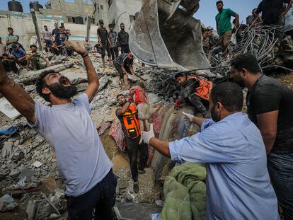 Palestinos recuperan el cuerpo sin vida de una niña de entre los escombros de la vivienda de la familia palestina Al Faseih, tras un ataque israelí sobre el campo de refugiados de Al Shatea, este martes.