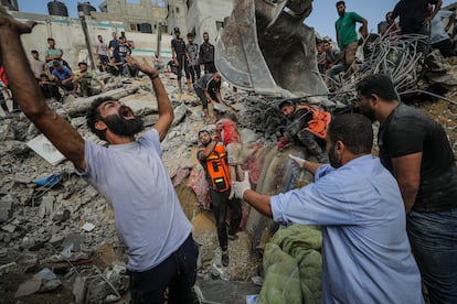Palestinos recuperan el cuerpo sin vida de una niña de entre los escombros de la vivienda de la familia palestina Al Faseih, tras un ataque israelí sobre el campo de refugiados de Al Shatea, este martes.