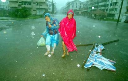 Dos mujeres atraviesan una calle bajo una intensa lluvia en Cangnan, en la provincia de Zhejiang, al este de China.