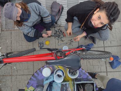 Dos colaboradoas del Taller de Bicis del Vecindario, reparan una bicicleta, en Córdoba (Argentina).
