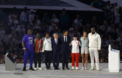 El presidente del COI, Thomas Bach, y el presidente del Comité Organizador de París 2024, Tony Estanguet, con traje los dos,  posan con atletas durante la ceremonia de clausura de los Juegos Olímpicos de Verano de 2024.