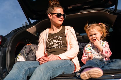 Una madre y su hija descansan en el maletero del coche.