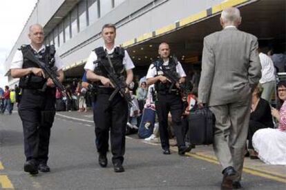 Policías británicos patrullan fuera de la terminal 1 del aeropuerto de Heathrow, donde esperan decenas de pasajeros.