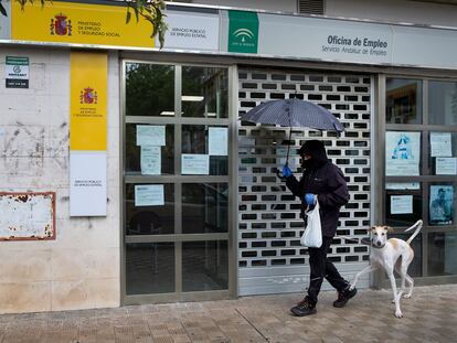 Un hombre pasa con su perro por delante de una oficina de empleo cerrada, este mes de abril en Sevilla.