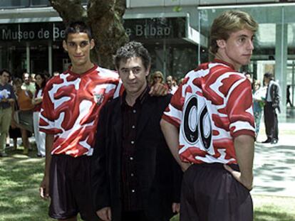 El pintor Darío Urzay posa junto a dos juveniles del Athletic que lucen la nueva camiseta del equipo.