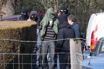 Efectivos de la Gerdarmería francesa sacan, exposado y con la cara cubierta por una chaqueta verde, a uno de los tres miembros de ETA detenidos en la localidad de Cahan.