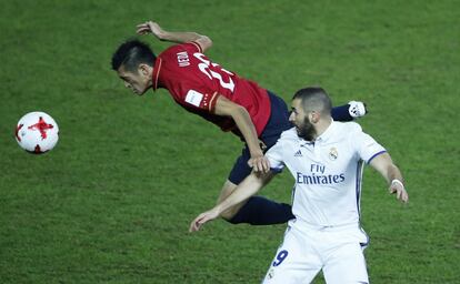 Naomichi Ueda, del Kashima Antlers, golpea el balón de cabeza ante la presencia de Benzema, del Real Madrid.