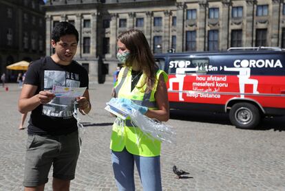 Una joven reparte mascarillas y folletos informativos sobre su uso en las calles de Ámsterdam.