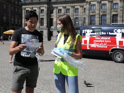 Una joven reparte mascarillas y folletos informativos sobre su uso en las calles de Ámsterdam.