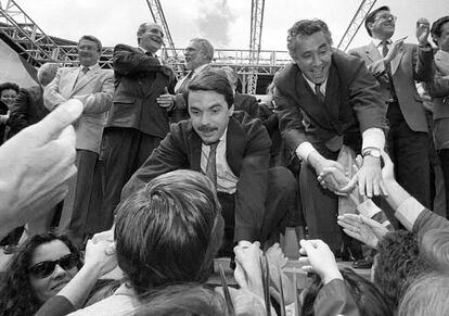 El presidente del PP, José María Aznar, y Javier Arenas, el 24 de abril de 1994, se agachan para saludar a un grupo de simpatizantes en la plaza de toros de Granada tras la presentación de los candidatos del PP en las elecciones andaluzas del 12 de junio.