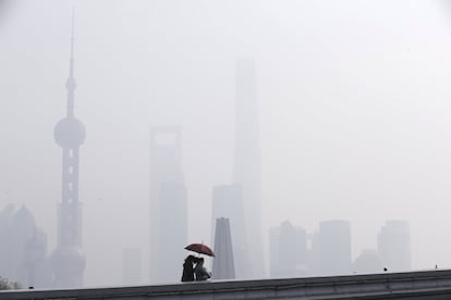 Unas mujeres caminan bajo una densa capa de polución en el distrito financiero de Shangai, China.