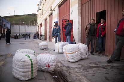 En la puerta de las naves, varios hombres esperan con los bultos para tratar de llegar a un acuerdo negociando el precio con las porteadoras.