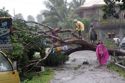 Varios vecinos del municipio de Mabini cortan árboles que bloquean la carretera después de las intensas lluvias y fuertes vientos, provocados por el tifón.