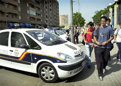 Un coche de la Policía Nacional, ayer a la salida del instituto de Orriols, a cuyas puertas se concentra un grupo que amenaza a estudiantes inmigrantes.