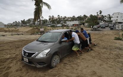 Un grupo de hombres intentan mover un coche atascado en la arena, en Cabo San Lucas el 6 de septiembre.