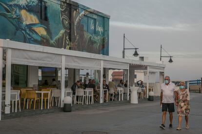 Una pareja pasa por delante de un restaurante en el puerto de Corralejo, en Fuerteventura, el 3 de octubre.