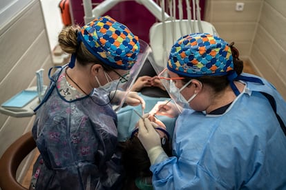 Dos profesionales atienden a un paciente en una clínica dental madrileña.