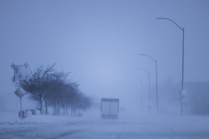 Vehicles navigate snowy roads during a blizzard in Waukee, Iowa, USA