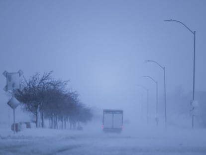 Vehicles navigate snowy roads during a blizzard in Waukee, Iowa, USA