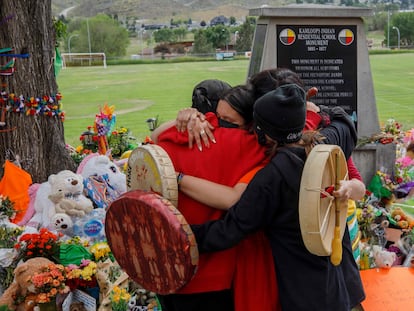 Miembros de la comunidad Mosakahiken Cree Nation se abrazan frente a un monumento en homenaje a las 215 tumbas de niños halladas en el antiguo internado Kamloops para indígenas en Columbia Británica.