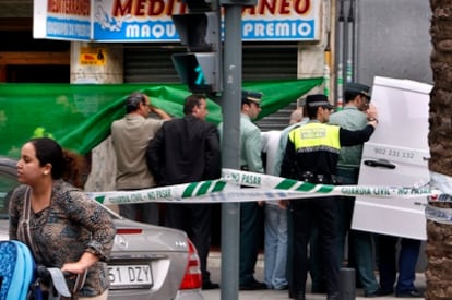 El traslado del cadáver de la víctima a un furgón se ha realizado tras un lona verde colocada ante el local.