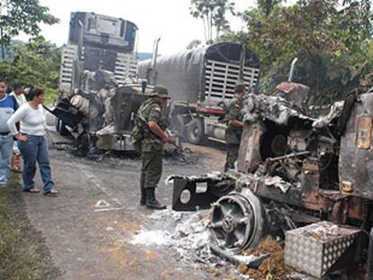 Varios soldados observan los restos de tres camiones de gran tonelaje incendiados el sábado en la carretera entre Buenaventura y Cali.