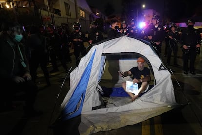 Un manifestante instala una carpa frente a la policía en la sección Echo Park de Los Ángeles, el día de ayer.