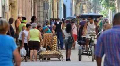 Dos cuentapropistas cubanos, un vendedor de productos agropecuarios (i) y un "Bicitaxi" (d), se movilizan por las calles de La Habana (Cuba).