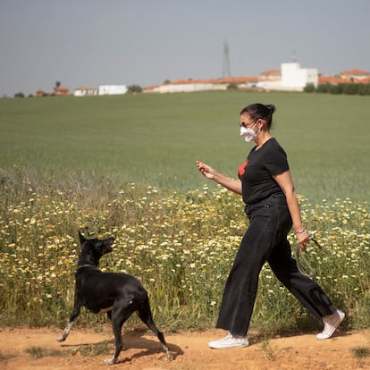 Una mujer con alergia camina por el campo junto a su perro protegida del polen con una mascarilla FFP2.