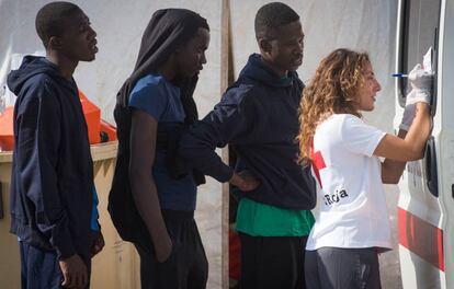 Una voluntaria de Cruz Roja atiende a varios inmigrantes ayer en Algeciras.