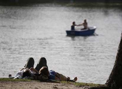 Una pareja tumbada en la hierba disfrutaba ayer del buen tiempo en el parque del Retiro.